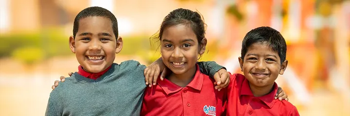 Three smiling ACTS HOUSE OF EDUCATION learners with their arms around each other