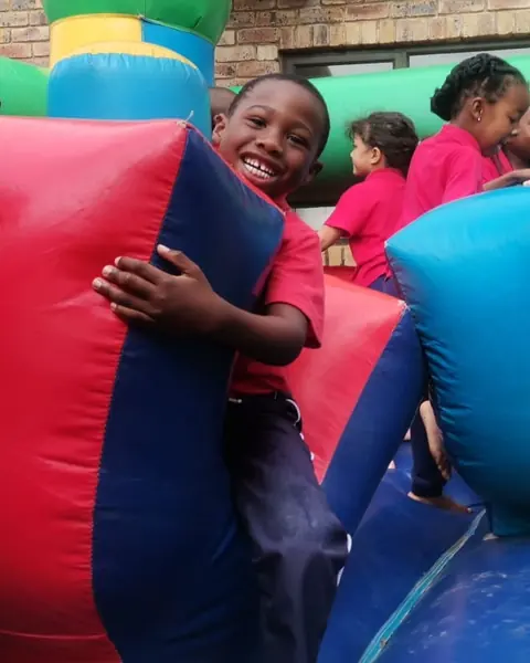A grinning boy hugging a big inflatable on a jumping castle
