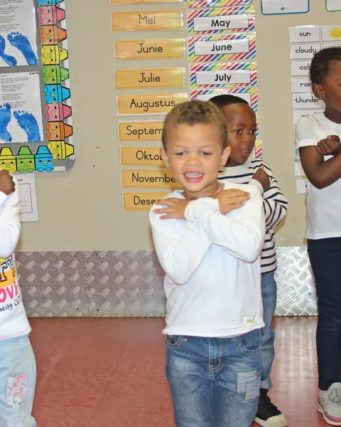 Children in white shirts striking a pose in front of their class calendar